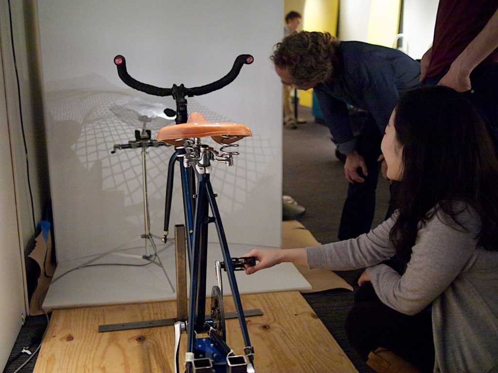 Picture of student working on kinetic sculpture involving a bicycle.